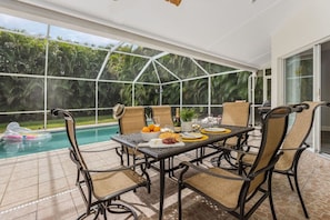 Fully screened pool area with loungers, conversational seating, outdoor dining and a gas grill