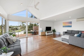 The upper level features a bright, open plan living area with cathedral ceilings