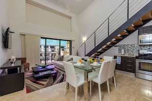 Ample living space with dining table, television, and well-equipped kitchen.