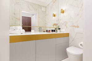 Modern bathroom with a shower, sink with mirror, toilet and washing machine.