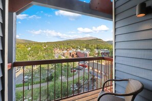 The view of the private outdoor balcony with stunning river, forest, and mountain views as seen in summer.