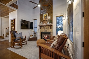 The living room has a stone fireplace at the heart of it.