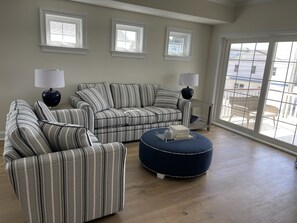 Living room with full sized couch, love seat, cocktail ottoman, cocktail tables