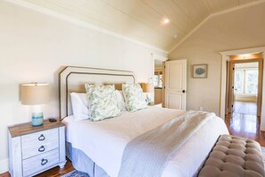 The master bedroom features a king bed, night stands with reading lamps and vaulted shiplap ceilings.