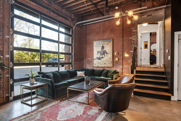 Spacious living room with large couch that turns into sleeper sofa. Unique glass garage door! Plus a 65' smart TV with Sonos! This condo has its own private entrance.