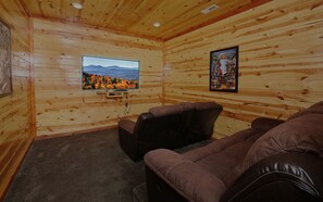 Private theater room with tiered seating and large screen TV.