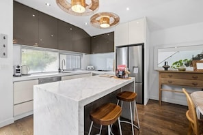 The kitchen is equipped with quality stainless steel appliances, marble benchtops, and stylish cabinetry for elevated living