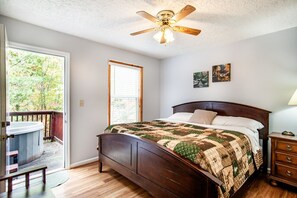 This cozy bedroom, complete with warm tones and a private deck leading to a hot tub, is the ultimate retreat.