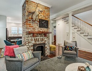 The exposed brick of the decorative fireplace gives a glimpse into the historic nature of the home, while modern West Elm furnishings create a comfortable space to relax.