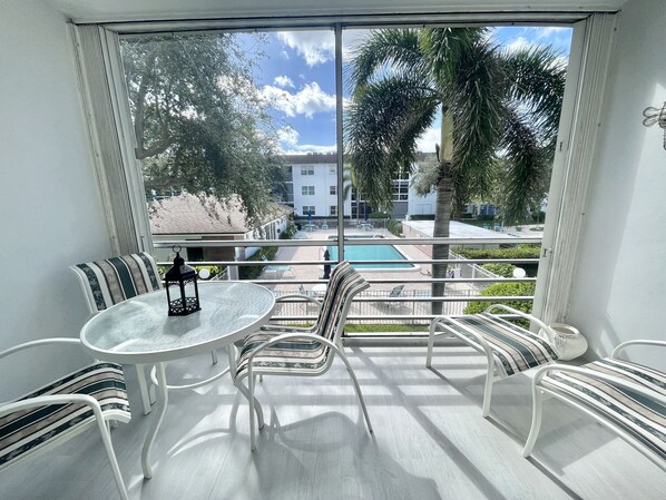 Screened balcony overlooking the pool has dining table and chairs for relaxing. 