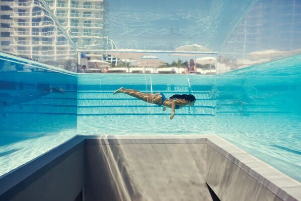 The pool features a stunning glass-encased centerpiece staircase. 