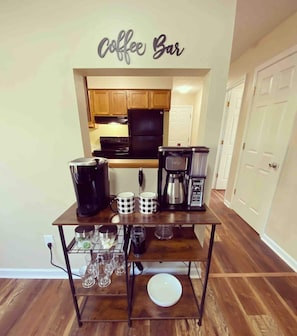 Fully stocked coffee bar with Keurig, drip coffeepot, and milk frother.