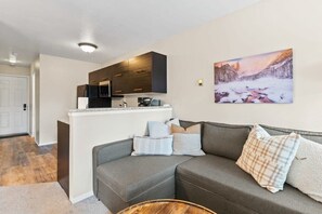 View of the living room, fully-equipped kitchen, and front door entrance