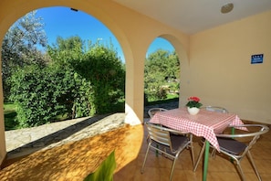 The large terrace at the entrance with table and chairs overlooking the garden.