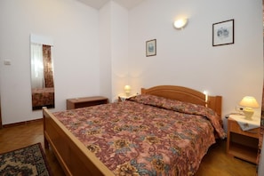 The bedroom with double bed, two bedside tables with night lamps, mirror.