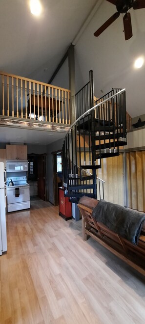 View of kitchen, door to downstairs bedroom, bathroom, spiral stairs to loft.