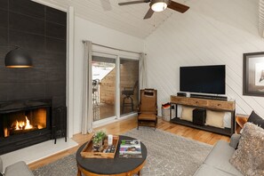 The open plan living area features high vaulted ceilings and a gas fireplace