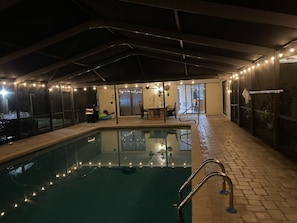 Covered and heated pool at night, looking looking at entrances