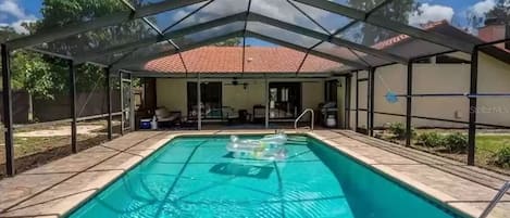 Covered and heated pool during the daytime looking back at house