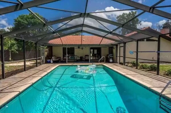 Covered and heated pool during the daytime looking back at house