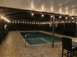 Covered and heated pool at night, looking from kitchen entrance