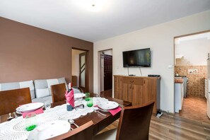 Living room with a sofa bed, TV and dining area.