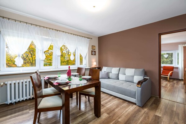 Living room with a sofa bed, TV, dining area.