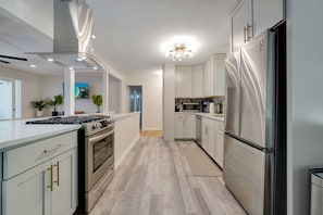 Kitchen with beautiful quartz countertops modern lighting & stainless appliances