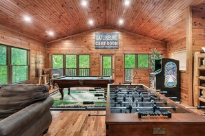 Everyone will be entertained in the upper level game room.  Play pool, foosball, arcade games, or board games.  The abundant windows and high ceilings make this room bright, airy, and large enough for the whole family.