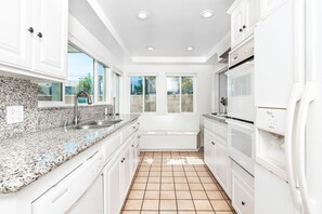 Beyond the living area is the kitchen, which comes stocked with dishes, utensils, cookware, bakeware, and large and small appliances.
                