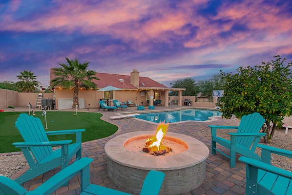 amazing backyard, complete with heated pool, hot tub, patio lounge and dining table, fire pit and even a putting green to practice your skills.