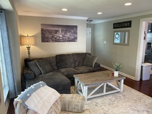 Main floor living room with large picture window, electric fireplace and 65" TV