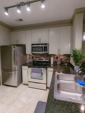 The large, open kitchen has stone counters and brand new appliances