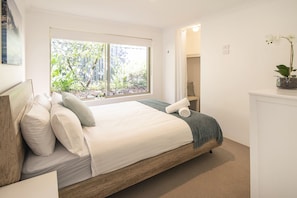 Relax in the primary bedroom with a queen bed, walk-in wardrobe, and soft natural tones that create a peaceful retreat.