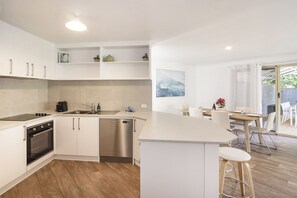 Cooking is a breeze in this sleek, open kitchen featuring a Nespresso coffee machine, stainless steel appliances, and a convenient breakfast bar.