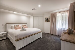 Relax in the spacious first bedroom, featuring a plush king-sized bed, soft lighting, and calming décor for ultimate comfort.