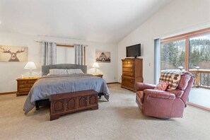 Master bedroom, on the upper level of the home, with a beautiful king-size bed, lounge seating, a flat-screen TV, access to a private outdoor deck, and an en suite bathroom