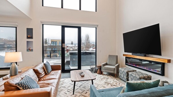 Open concept living room with gas fireplace and SmartTV, dining area, and kitchen with wrap around balcony and hot tub