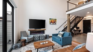 Open concept living room with gas fireplace and SmartTV, dining area, and kitchen with wrap around balcony and hot tub