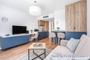 A sleek open-plan living room with a dining area, modern furniture, and natural light.

