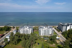 An aerial view of a seaside neighborhood, highlighting modern architecture and lush greenery.
