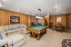 Downstairs game room with L shaped couch, pool table, and card table