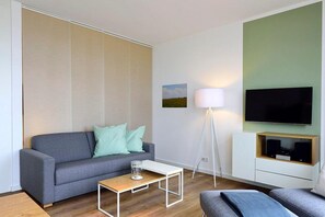 Wohn/ Essbereich mit Couch, Tisch und Fernseher