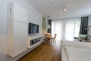 Wohn-Ess-Schlafbereich mit Sofa, Esstisch, und Doppelbett sowie Flatscreen TV