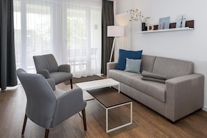 Wohn-Essbereich mit Couch und Zugang zum Balkon