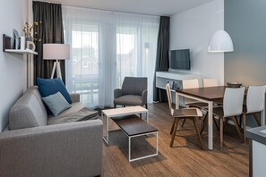 Wohn-Essbereich mit Couch, Esstisch, Sitzgelegenheit und Zugang zum Balkon
