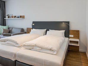 Wohn-Ess-Schlafbereich mit Sofa, Esstisch, Sitzgelegenheit und Doppelbett sowie Zugang zum Balkon