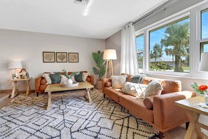 The cozy sitting room at the front of this great vacation home is flooded with sunlight, and furnished with leather sofa & loveseat.