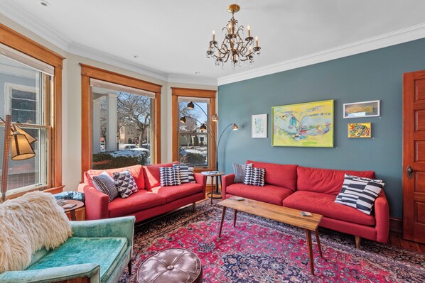 Large light & bright living room featuring regional artists work on gallery wall.
