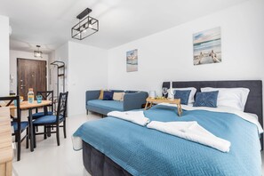 A bedroom with a double bed covered in blue bedding, a small nightstand with a lamp, and framed art on the wall, creating a cozy, restful space.